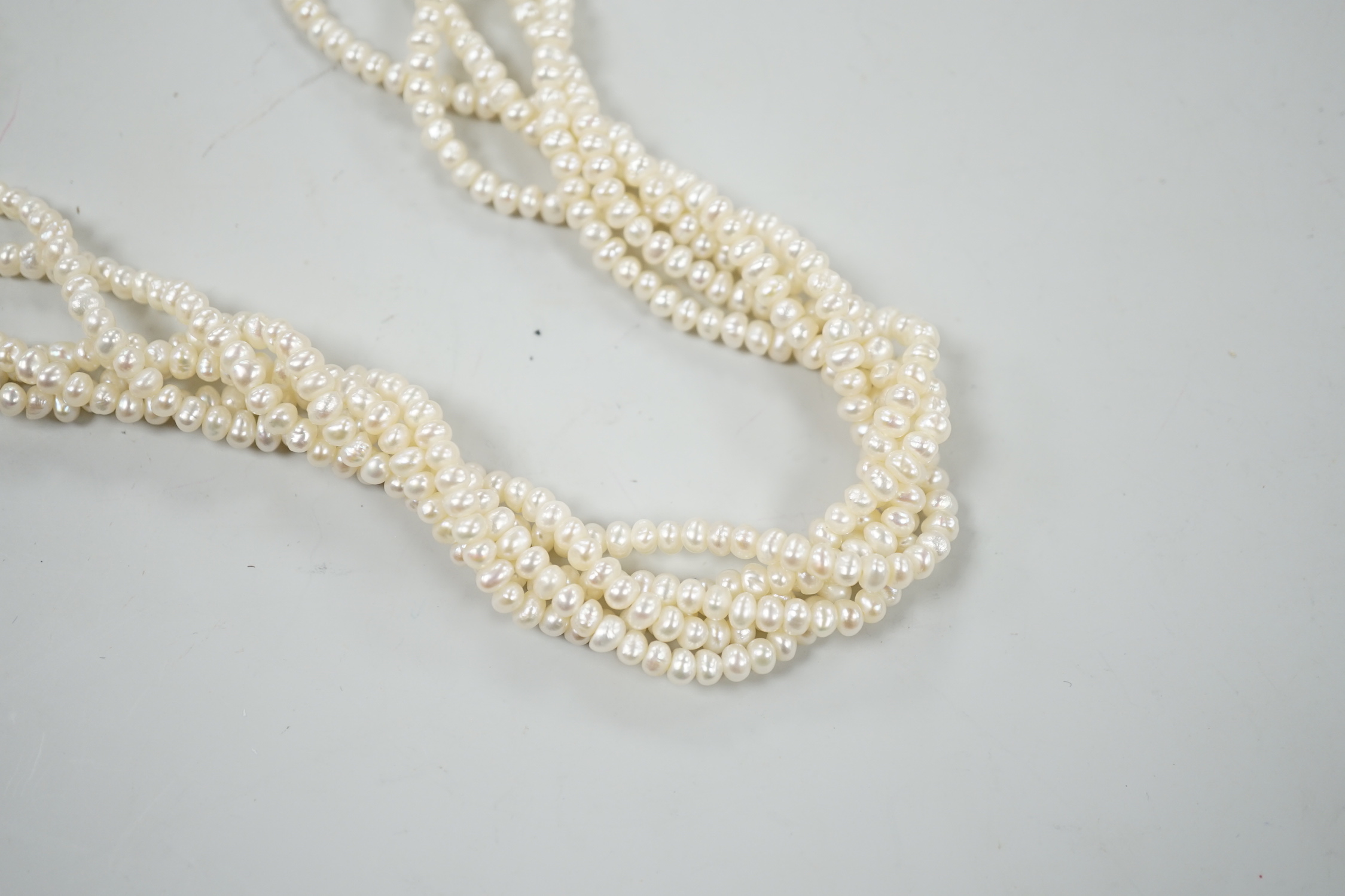 A cultured baroque pearl torsade choker necklace, with early yellow metal garnet and split pearl set clasp, 38cm.